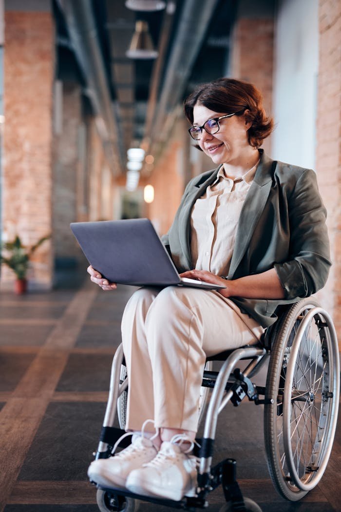 Photo of Woman Sitting on Wheelchair While Using Laptop